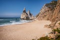 Towering rock cliffs at Praia Da Ursa Beach, Sintra, Portugal. Atlantic ocean waves and sandy beach near famous Cabo Da