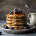 A towering stack of fluffy blueberry pancakes drizzled with maple syrup