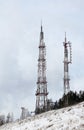 Towers or antennas of cellular communication 4G and 5G or television broadcasting against a cloudy sky on a mountain, winter Royalty Free Stock Photo