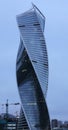 Towers of modern high-rise business centers made of glass and concrete against the background of gray sky. Light in windows