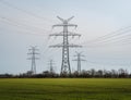 Towers with multiple power lines over a green field with blue sky