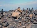 Towers of stacked pebbles and stones in different colours in a large arrangement on a black sand beach with blue sky Royalty Free Stock Photo