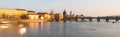 Towers of Prague Old Town and Charles Bridge over Vltava River illuminated by sunset. Panoramic view.