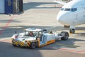 Towing a passenger plane using special equipment for aircraft maintenance. Departure flight in the background of the terminal