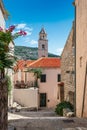 Clock tower behind traditional houses in alley with stairs in Dubrovnik old town in Croatia. Royalty Free Stock Photo