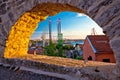 Town of Pula coast and shipyard cranes sunset view through stone