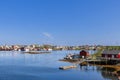 The town of Reine on Lofoten Island, Norway, enjoys a calm sea and a jagged, rocky shoreline under a clear blue sky