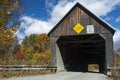Fall foliage surrounds the Linclon Covered Bridge over the Ottauquechee River in West Woodstock Vermont.