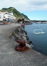 Marina and waterfront bathing pool, rusty mooring cleat on the concrete berth in the forefront, Povoacao, Sao Miguel Island, Azore