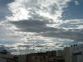 Town under a hidden sun and white clouds travelling.Evening clouds over the town. Ciudad cubierta de nubes