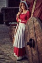 Townswoman in red dress with an apron and chaperone on the street.