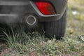 Toxic CO2 exhaust fumes from the exhaust pipe of a car parked on the lawn. Royalty Free Stock Photo