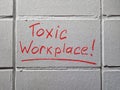 Toxic workplace words handwritten on the wall. Royalty Free Stock Photo