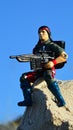 Toy action figure of GI Joe team member named Spirit, sitting on coastal rock with explosive arrow rifle