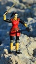 Toy action figure of GI Joe team named Jinx standing on coastal rocks with two sword models