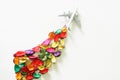 Toy airliner with a contrail of colorful flower petals. Concept of eco-friendly biofuel, alternative energy and green revolution.