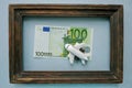 The toy airplane is located on a 100 Euro banknote in a vintage wooden frame on a blue background Royalty Free Stock Photo