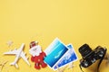 Toy airplane, photos and camera on a yellow background with copy space. Christmas Travel Planning Concept