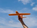 A toy airplane in your hand flies up and forward against a blue sky on a sunny day, a symbol of movement, growth and development,