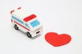 Toy ambulance car and abstract red heart on white background. Royalty Free Stock Photo