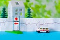 Toy ambulance car cardiogram house tree blue green hospital sign background