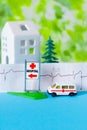 Toy ambulance car cardiogram house tree blue green hospital sign background