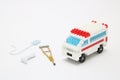 Toy ambulance car, miniature drop, gibbs, and crutch on white background.