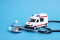 Toy ambulance car and stethoscope on blue background Royalty Free Stock Photo