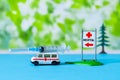 Toy ambulance car syringe blue green hospital sign background covid 19