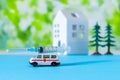 Toy ambulance car syringe blue green hospital sign background house covid 19 tree