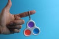 Toy anti-stress popit simple dimple in hand on a blue background