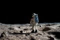 The toy of the astronaut stands on the moon\'s surface Royalty Free Stock Photo