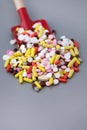 Toy baby scoop full of multi-colored pharmaceutical pills and capsules Royalty Free Stock Photo