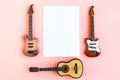 Toy bass, acoustic and electric guitars and white mockup blank on pink background, top view Royalty Free Stock Photo