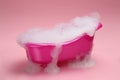 Toy bathtub overflowing with foam on pink background Royalty Free Stock Photo