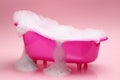 Toy bathtub overflowing with foam on pink background Royalty Free Stock Photo