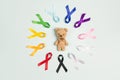 Toy bear with circle of colorful awareness ribbons on blue background. World cancer day concept, February 4