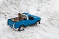 A toy. Blue pickup truck in winter forest on the road. Carrying fir cones in the back of a car body Royalty Free Stock Photo