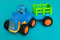 Toy blue tractor with a trailer on a blue background.Close-up. Royalty Free Stock Photo