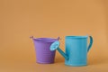 Toy blue watering can and purple bucket on an orange background Royalty Free Stock Photo