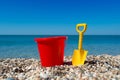 Toy bucket and spade on the beach stones Royalty Free Stock Photo