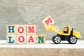 Toy bulldozer hold block e to complete word home loan to on wood background