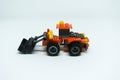 Toy bulldozer made from mostly orange and black plastic bricks.