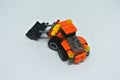 Toy bulldozer made from mostly orange and black plastic bricks.