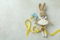 Toy bunny, child cancer awareness ribbon and pacifier on white textured background