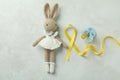 Toy bunny, child cancer awareness ribbon and pacifier on white textured background