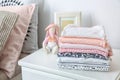 Toy bunny and stack of child clothes on table indoors Royalty Free Stock Photo