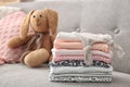 Toy bunny and stack of child clothes on sofa Royalty Free Stock Photo