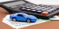 Toy car, calculator and pen on a brown background. Car rental, purchase or insurance. Royalty Free Stock Photo