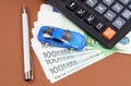 Toy car, calculator and pen on a brown background. Car rental, purchase or insurance. Royalty Free Stock Photo